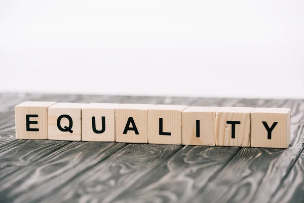 Equality lettering made from alphabet cubes on wooden table on white — Stock Photo