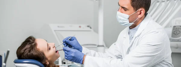 Стоматолог в маске и латексных перчатках, осматривающий зубы женщины в стоматологической клинике — стоковое фото