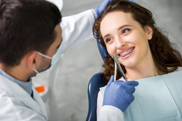 Selektiver Fokus der lächelnden Frau beim Anblick des Zahnarztes während der Untersuchung — Stockfoto