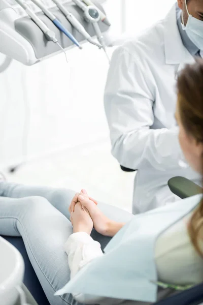 Enfoque selectivo de la mujer sentada en la silla cerca del dentista - foto de stock