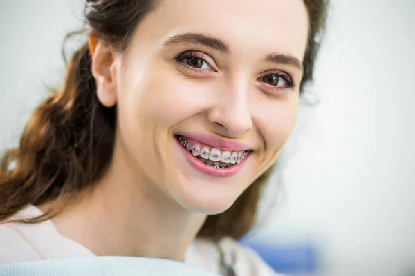 Close up de mulher feliz com aparelho nos dentes sorrindo na clínica odontológica — Fotografia de Stock