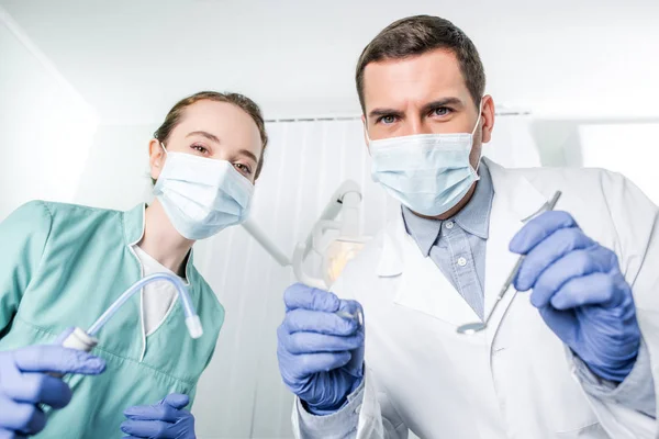 Dentistas con máscaras que sostienen instrumentos dentales en las manos - foto de stock