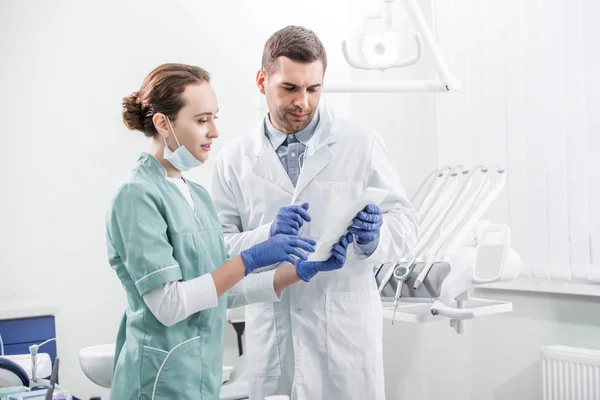 Zahnärzte stehen in Zahnklinik und schauen auf digitales Tablet — Stockfoto