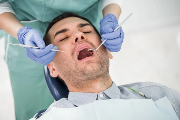 Vue recadrée d'une dentiste travaillant avec une patiente à bouche ouverte — Photo de stock