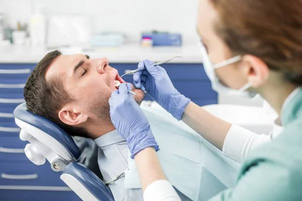 Selective focus of patient with opened mouth near female dentist in mask with dental instruments — Stock Photo