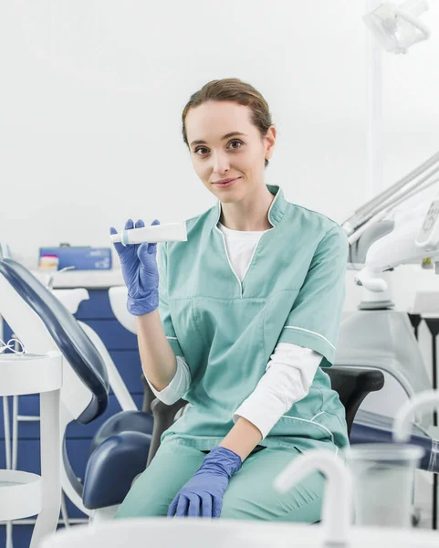 Селективное внимание веселой женщины-стоматолога, держащей зубную пасту — стоковое фото
