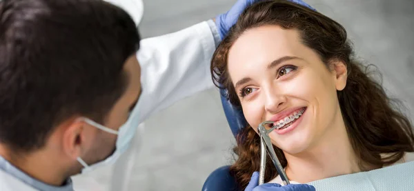 Messa a fuoco selettiva di donna attraente sorridente mentre si guarda dentista durante l'esame — Foto stock