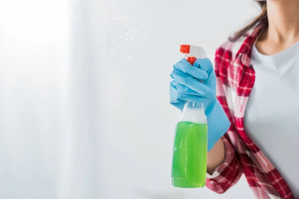 Vista parcial de mujer afroamericana sosteniendo botella de spray sobre fondo blanco - foto de stock