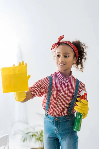 Mignon enfant afro-américain avec chiffon jaune et vaporisateur vert — Photo de stock