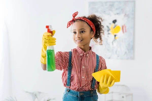 Sorridente bambino africano americano pulizia casa in guanti di gomma gialla — Foto stock