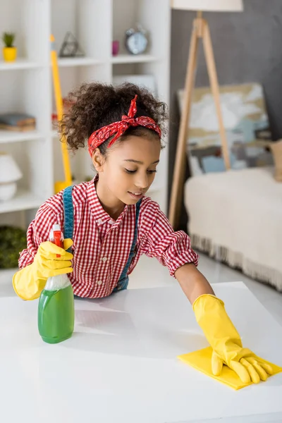 Adorable african american child cleaning table with yellow rag — Stock Photo