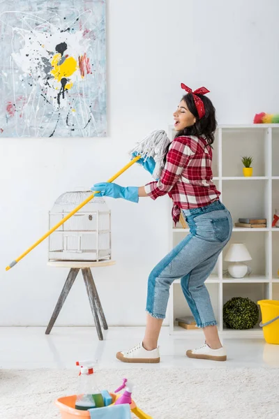 Fröhliche afrikanisch-amerikanische Frau singt mit Wischmopp — Stockfoto