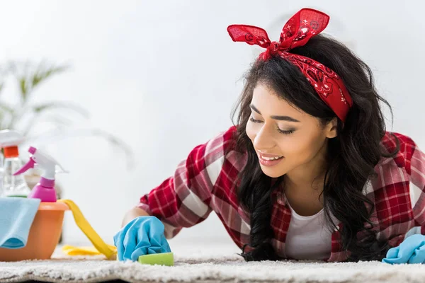 Hübsche Afroamerikanerin im karierten Hemd putzt Teppich — Stockfoto