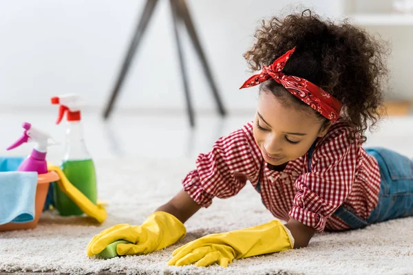 Carino africano americano bambino tappeto di pulizia in guanti di gomma gialla — Foto stock