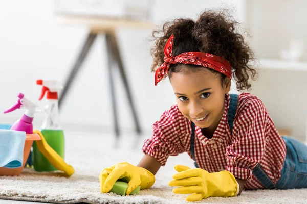 Adorable alfombra de limpieza infantil afroamericana en guantes de goma amarillos - foto de stock
