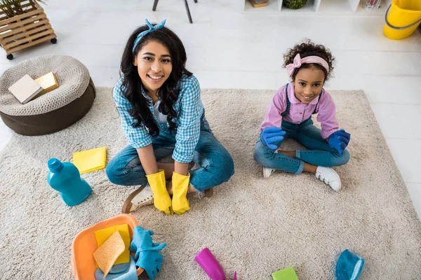 Smiling african american mother and daughter sitting on carpet in lotus poses — Stock Photo