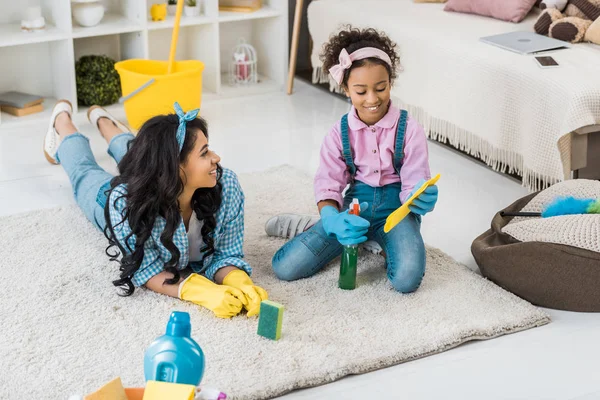 Smiling african american child sitting on carpet while cute daughter sitting near — Stock Photo