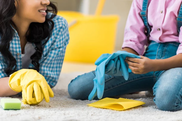 Vista parcial de la madre y la hija afroamericanas descansando sobre una alfombra - foto de stock