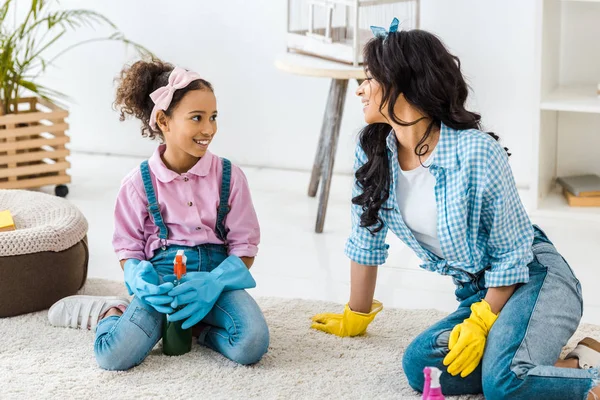 African american mother and daughter talking while sitting on carpet — Stock Photo