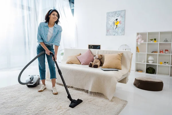 Attractive african american woman cleaning carpet with vacuum cleaner — Stock Photo