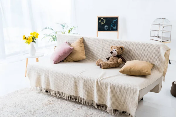Chambre spacieuse et lumineuse avec canapé confortable avec oreillers et ours en peluche — Photo de stock