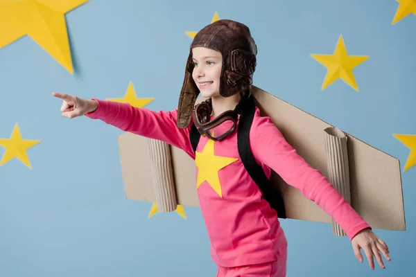 Happy child in flight helmet having fun on blue background with stars — Stock Photo