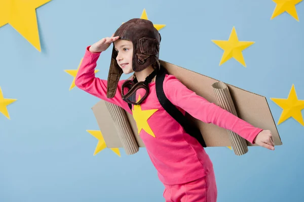 Enfant mignon dans le casque de vol posant sur fond bleu étoilé — Photo de stock