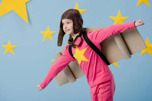 Funny kid in cardboard wings flying on blue starry background — Stock Photo