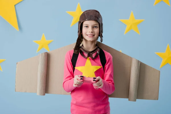 Smiling kid in flight helmet holding joystick on blue starry background — Stock Photo