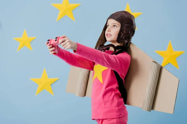 Concentrated kid with joystick looking up on blue starry background — Stock Photo