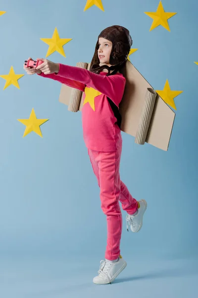 Preteen kid in flight helmet holding joystick on blue starry background — Stock Photo