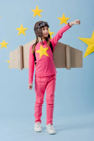 Preteen child in flight helmet standing with fist up on blue starry background — Stock Photo