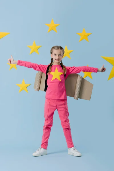 Kind mit Zöpfen zeigt Daumen nach oben auf blauem Sternenhintergrund — Stockfoto