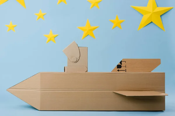 Cardboard rocket, helmet and stars on blue starry background — Stock Photo