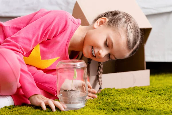 Smiling child looking at plant in glass jar with interest — Stock Photo