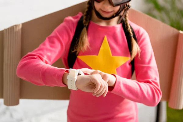 Abgeschnittene Ansicht eines Kindes mit Pappflügeln, das auf die Uhr schaut — Stockfoto