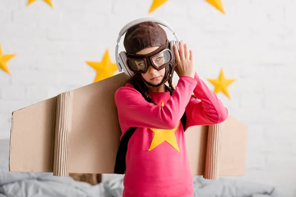 Triste enfant dans le casque de vol et lunettes écouter de la musique dans les écouteurs — Photo de stock