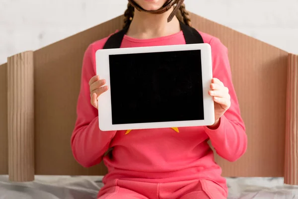 Vista recortada del niño con alas de cartón que sostiene la tableta digital con pantalla en blanco - foto de stock