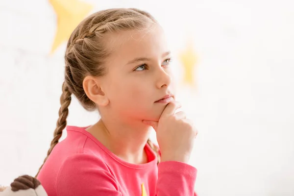 Adorable thoughtful child with braids touching chin — Stock Photo