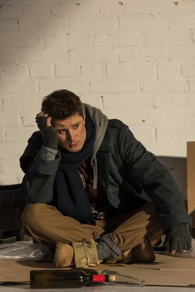 Депресивний безпритульний чоловік сидить на картоні і підробляє голову рукою — стокове фото