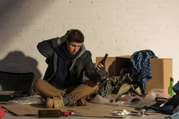 Disappointed homeless man holding empty alcohol bottle — Stock Photo