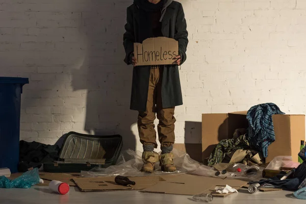 Vista recortada del hombre sin hogar sosteniendo un pedazo de cartón con texto escrito a mano 