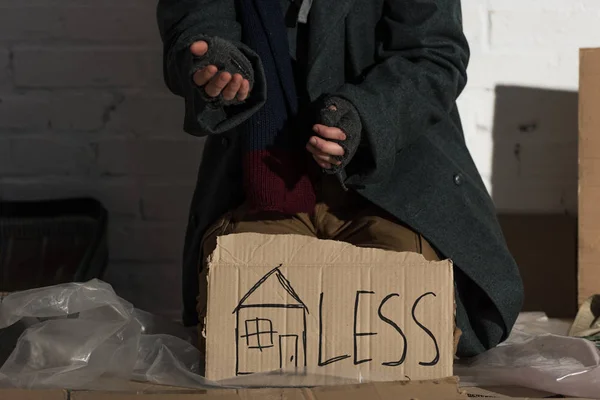 Partial view of begging man with symbol of house and 