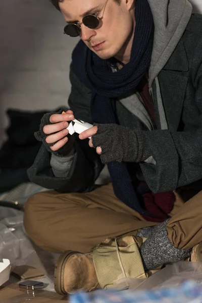 Hombre sin hogar en gafas oscuras conseguir cigarrillo de paquete - foto de stock