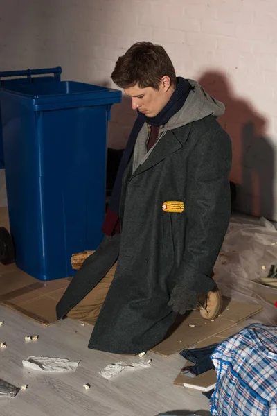 Депресивний безпритульний чоловік стоїть на колінах біля контейнера для сміття — стокове фото