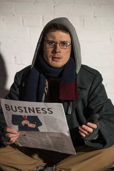 Homeless man reading business newspaper and looking at camera — Stock Photo