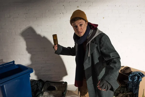 Angry drunk homeless man holding empty bottle while standing in threatening pose — Stock Photo