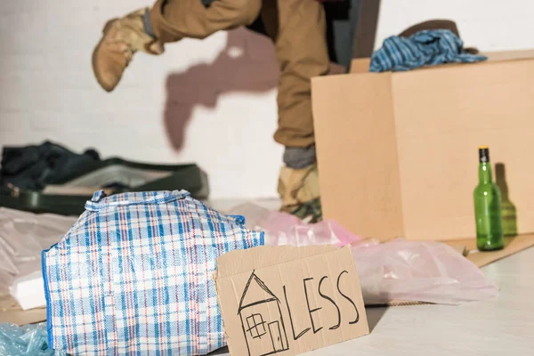 Cropped view of homeless man kicking cardboard box with garbage — Stock Photo