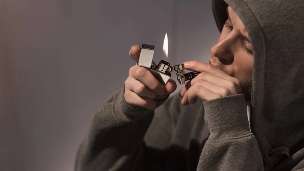 Selective focus of addicted man lightening smoking pipe with metallic lighter — Stock Photo