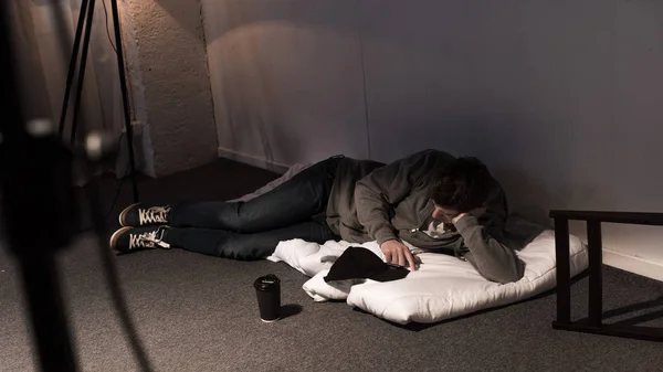 Mann liegt auf weißer Matratze auf dem Boden in dunklem Raum — Stockfoto
